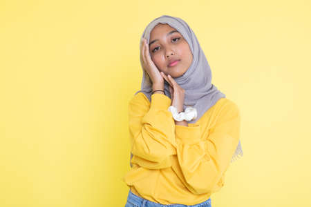 Fashion portrait of young beautiful asian muslim woman with wearing hijab isolated on yellow background.の写真素材