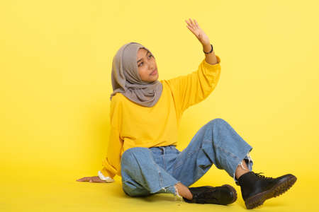 Fashion portrait of young beautiful asian muslim woman with wearing hijab isolated on yellow backgroundの写真素材
