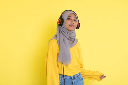 attractive asian woman listening music on yellow background.の写真素材
