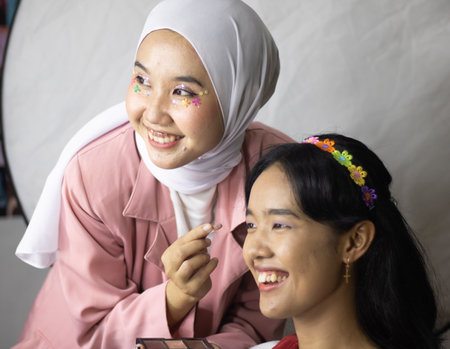 Two young sisters throwing confetti and looking happy on yellow backgroundの写真素材