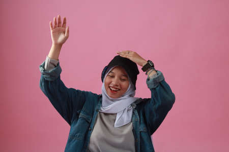 Fashion portrait of young beautiful asian muslim woman with wearing hijab isolated on pink background.の写真素材