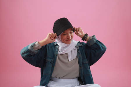 Fashion portrait of young beautiful asian muslim woman with wearing hijab isolated on pink background.の写真素材