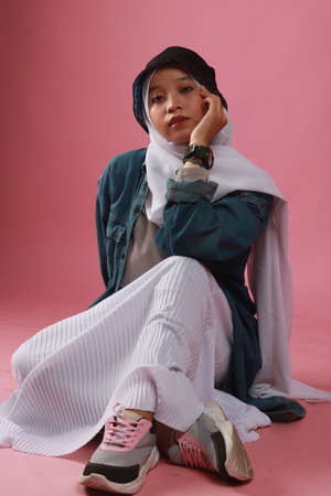 Fashion portrait of young beautiful asian muslim woman with wearing hijab isolated on pink background.の写真素材