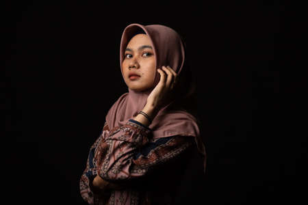 Fashion portrait of young beautiful asian muslim woman with wearing hijab isolated on black backgroundの写真素材