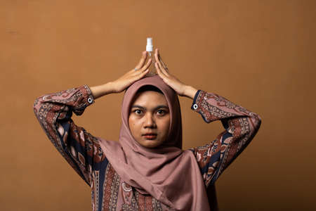 Asian young woman showing skincare products on gold background.の写真素材