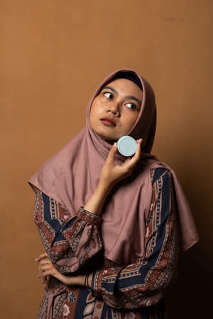 Asian young woman showing skincare products on gold background