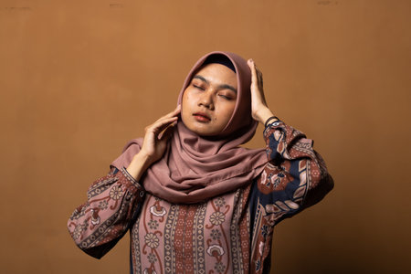 Fashion portrait of young beautiful asian muslim woman with wearing hijab isolated on gold...