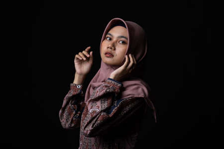 Fashion portrait of young beautiful asian muslim woman with wearing hijab isolated on black backgroundの写真素材