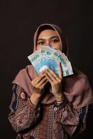 Happy young woman with cash money on black backgroundの写真素材