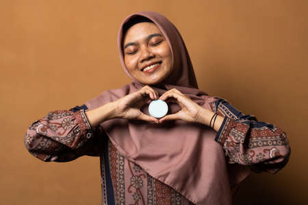 Asian young woman showing skincare products on gold background.の写真素材