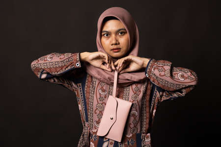 Young asian woman holding a wallet on black background