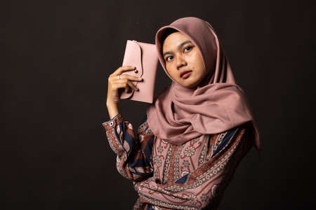 Young asian woman holding a wallet on black background