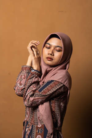 Fashion portrait of young beautiful asian muslim woman with wearing hijab isolated on gold...