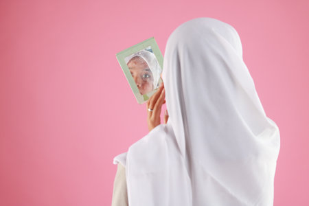 beautiful young asian woman looking at self in mirror.の写真素材