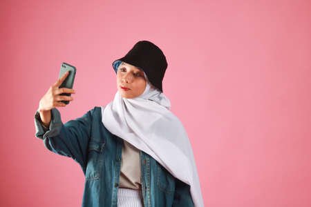 Fashion portrait of young beautiful asian muslim woman with wearing hijab isolated on pink...
