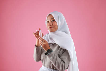 Asian young woman showing skincare products on pink background.の写真素材