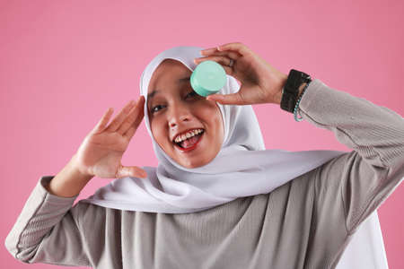 Asian young woman showing skincare products on pink background.の写真素材