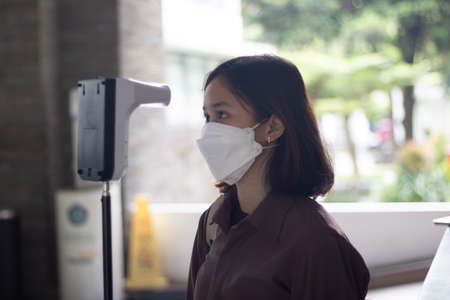 The Asian student woman has checked body temperature with a thermal Temperature scanner detector.の写真素材
