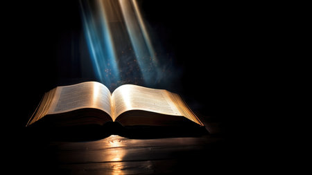 Open bible on a dark background with rays of light coming out from the pagesの素材