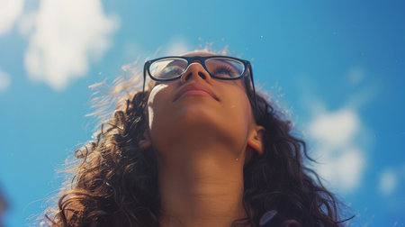 Portrait of a young woman with glasses against the blue sky.の素材