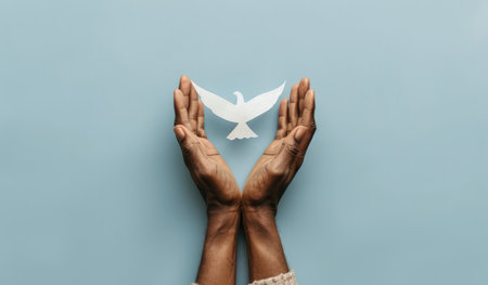 Praying hands with white paper dove on blue background, top viewの素材
