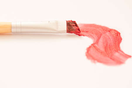 red lipstick stroke and makeup brush on white