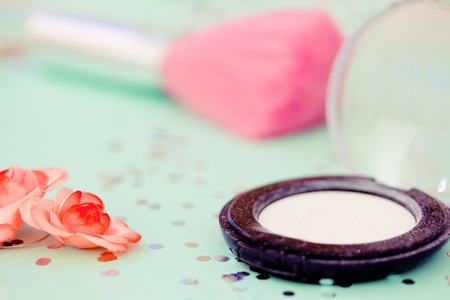 white eyeshadow and pink brush on teal background