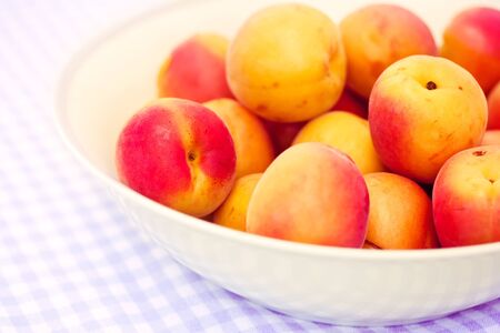 a bowl of some fresh apricots on summer tableclothの写真素材