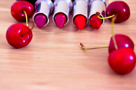 different tones of red lipsticks surrounded by cherriesの写真素材