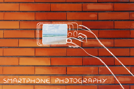 smartphone photography: person using phone camera to take a beach photoの写真素材