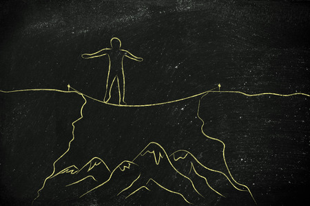 man successfully tight rope walking over a dangerous cliffの写真素材