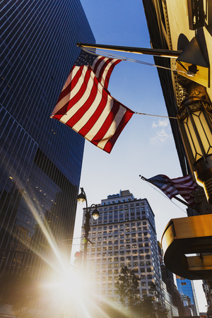 NEW YORK, NY - September 7th, 2017: Sunflare among buildings in Midtown Manhattan and American flags waving from the entrance of an hotelのeditorial素材