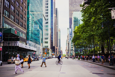 NEW YORK, NY - June 8th, 2014: Manhattan street with bike riders and pedestrians among iconic buildingsのeditorial素材