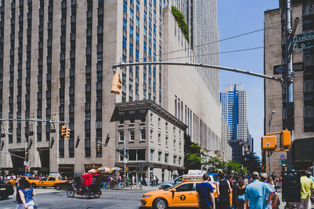 NEW YORK, NY - June 8th, 2014: Manhattan street with yellow cabs and pedestrians among iconic...
