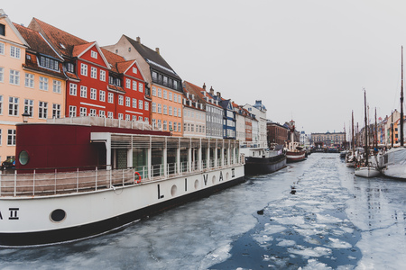 COPENHAGEN, DENMARK - March 11th, 2018: Copenhagen's famous Nyhavn harbour with the typical colorful houses and restaurants along the iced canals with traditional boatsのeditorial素材