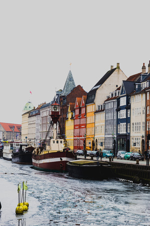 COPENHAGEN, DENMARK - March 11th, 2018: Copenhagen's famous Nyhavn harbour with the typical colorful houses and restaurants along the iced canals with traditional boatsのeditorial素材