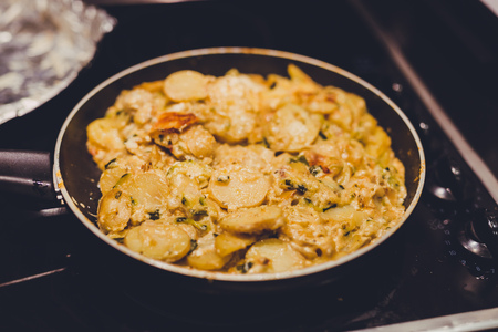 frying pan with potatoes, onions and zcchini recipe being cooked, close-up shot