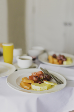 hotel breakfast table with plate of fruit, coffees and orange juices shot at shallow depth of fieldの写真素材