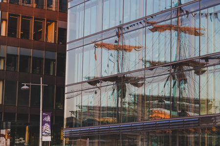 DUBLIN, IRELAND - June 3rd, 2018: heritage vessels reflected on the exterior of modern buildings in Dublin docklands during the Tall Ships Regatta 2018 at sunsetのeditorial素材