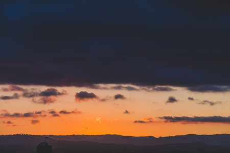 GOLD COAST, AUSTRALIA - January 15th, 2015: dramatic tropical sunset over Surfers Paradise with mountain viewのeditorial素材