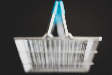 empty silver shopping basket on black, unfocused blurred backgroundの写真素材