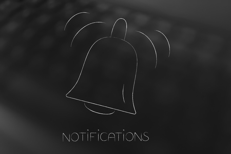 push notifications settings and marketing conceptual illustration: ringing notification bell icon on blurred keyboard backgroundの写真素材