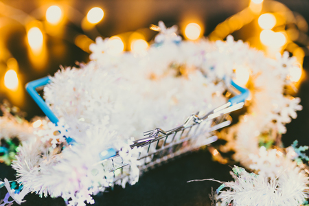 shining shopping cart with fairy lights and Christmas garland bokeh inside shot at shallow depth of field, metaphor of selling and promoting your best products for xmasの写真素材