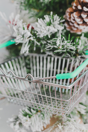 small Christmas tree with shopping basket hanging among its branches, concept of holiday shpping for food and presentsの写真素材