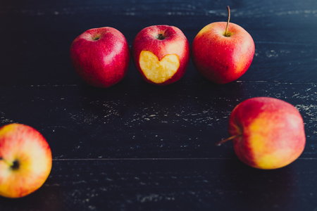 group of red apples with different tones on dark wooden table, healthy food conceptの写真素材