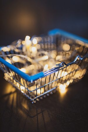 shining shopping cart with fairy lights bokeh inside shot at shallow depth of field, metaphor of selling and promoting your best productsの写真素材