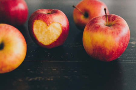 group of red apples with different tones on dark wooden table, healthy food conceptの写真素材