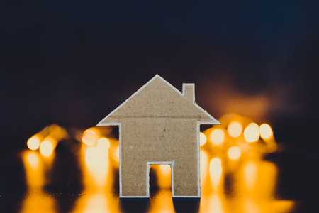 miniature house made of cardboard with fairy lights bokeh in the background like city lights, concept of looking for a property to buy or rentの写真素材