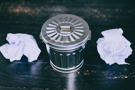 miniature garbage bin with paper balls to be thrown away, concept of drafting documents or trial and errorの写真素材
