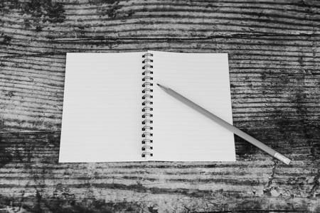 minimalist desk setting flatlay with opened ruled notepad and pencil on dark wooden surface with neutral tonesの写真素材